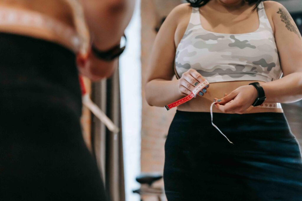 Woman measuring her waist with a tape measure