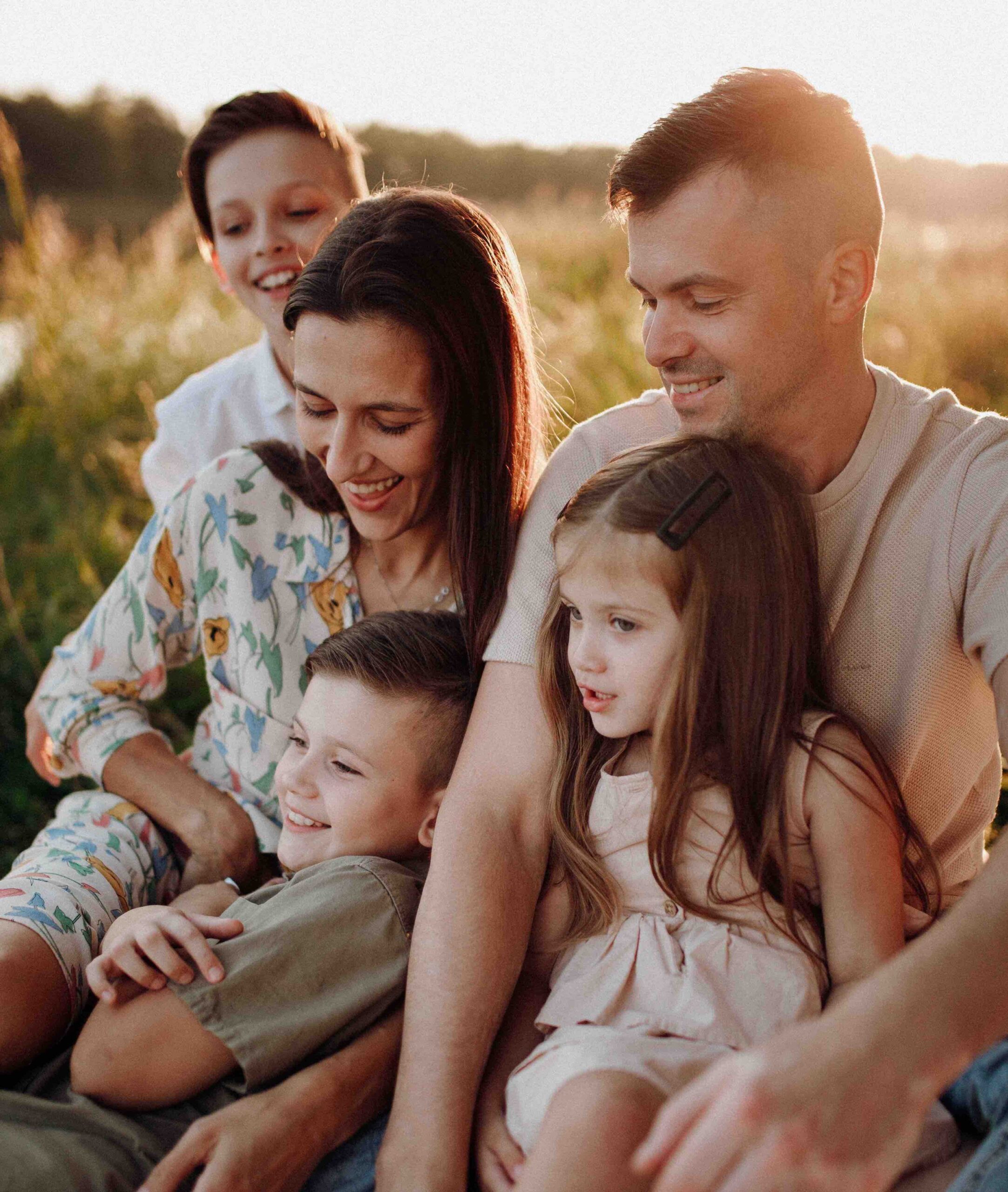 Smiling family outdoors with a father carrying a toddler on his shoulders